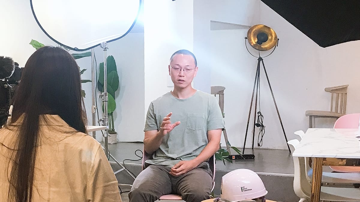 현대건설 안전모 아트 브랜드 캠페인 — 조명 앞에 앉아 인터뷰하는 작가